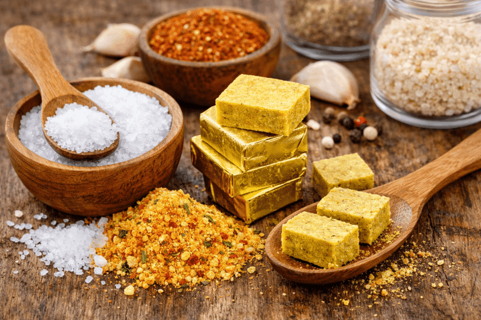 Salt, seasoning cubes, and seasoning powder on a wooden surface